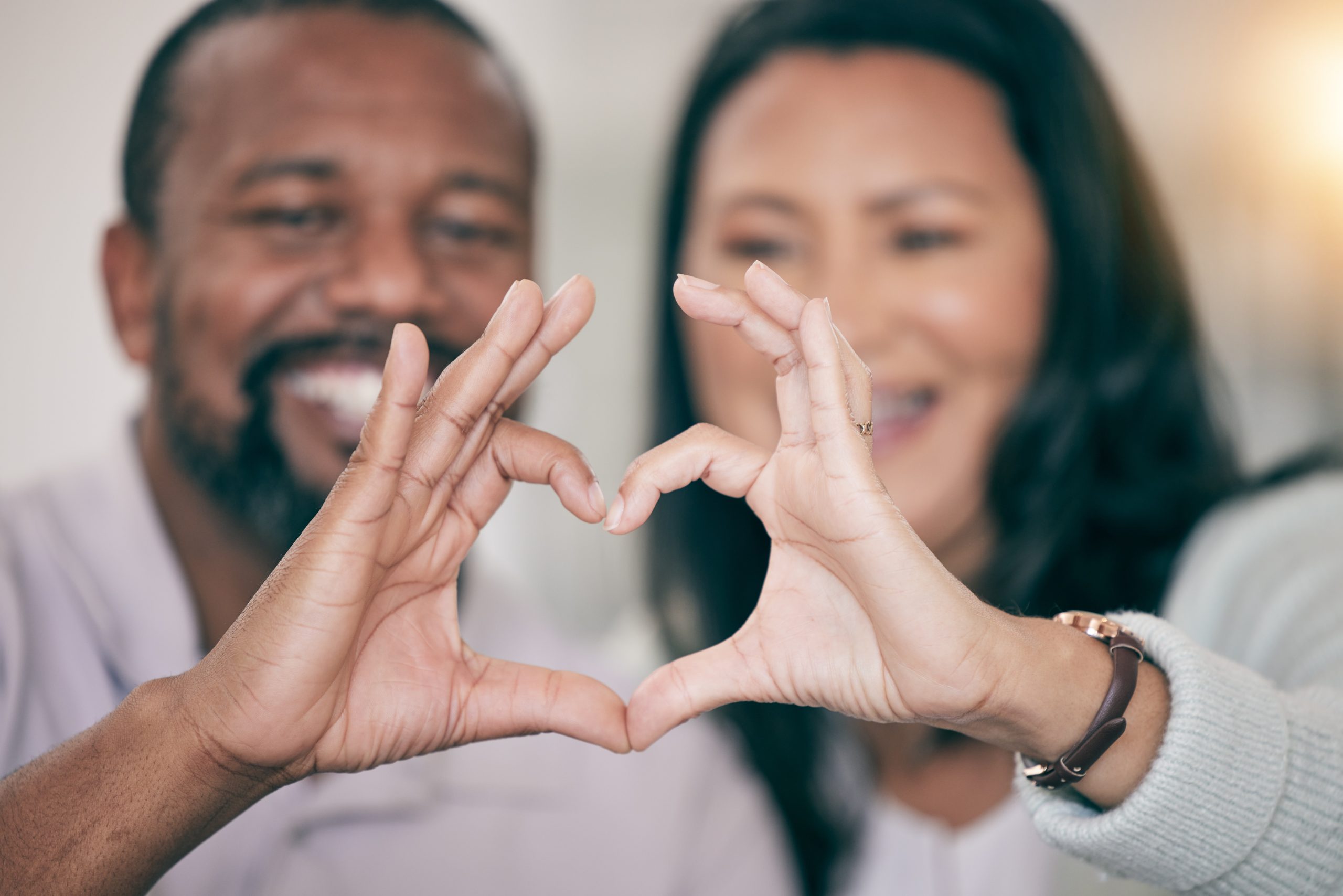 Hands, love and heart with a couple in their home to relax together in the living room closeup. Han.